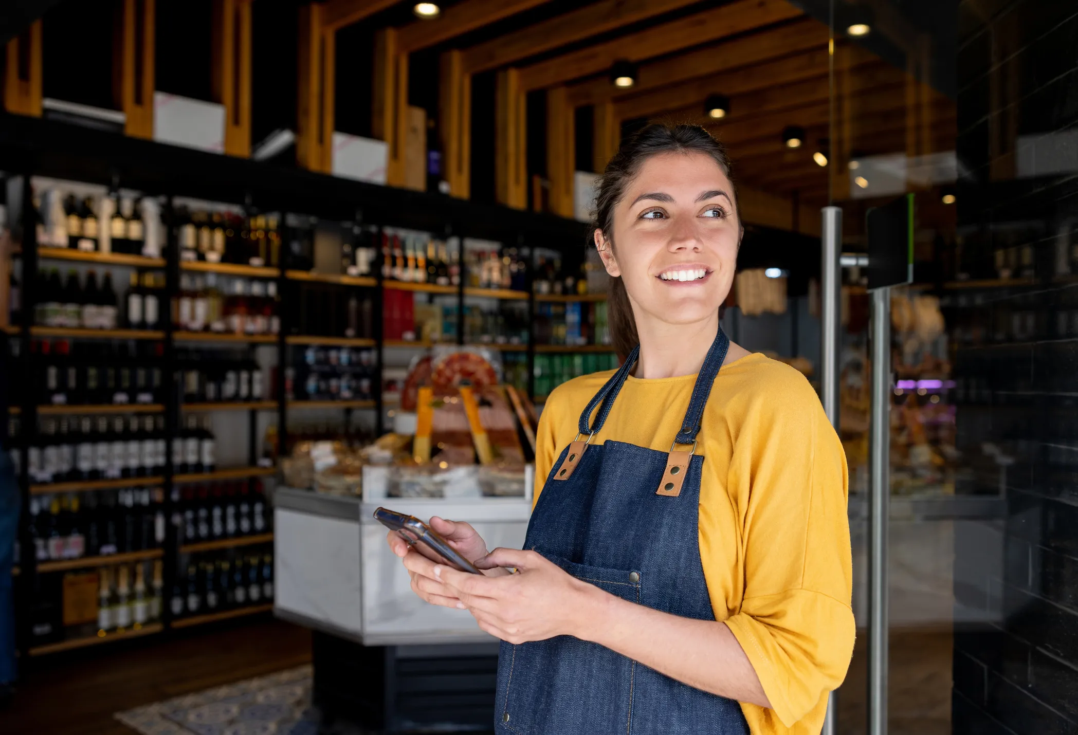 Comerciante local sonriente con el móvil en su tienda