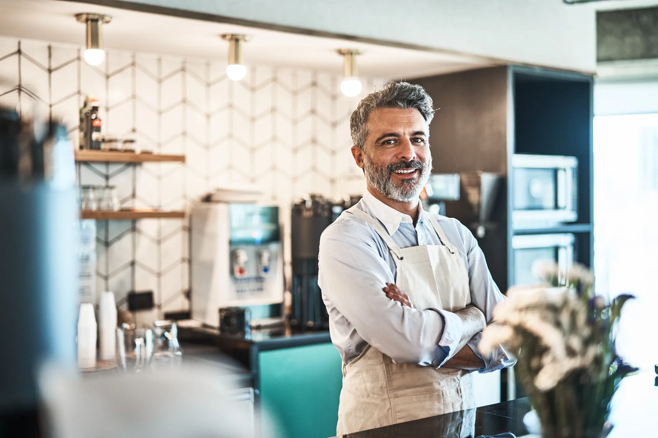 Dueño de una cafetería sonriente tras la barra de su local